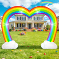 Rainbow heart-shaped arch inflatable with clouds at each base on a front lawn