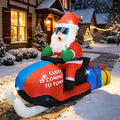 Santa in sunglasses riding a red Santa Is Coming to Town snowmobile inflatable in the snow