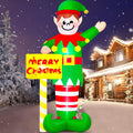 Giant elf inflatable waving beside a Merry Christmas street sign in a snowy yard