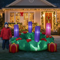 Advent wreath inflatable with three purple and one pink candle on a lawn beside a child