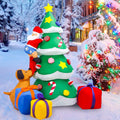 Inflatable Christmas tree with Santa climbing it and a dog pulling his boot, gifts at the base in the snow