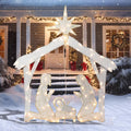 Glittered warm-lit nativity stable with a star and the Holy Family in front of a snowy porch