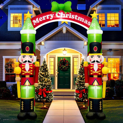 Two nutcracker soldiers holding a red Merry Christmas arch over a front walk at night