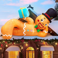 Gingerbread man inflatable in a top hat lying on a roof holding a blue gift