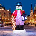 Snowman inflatable in a blue top hat holding a lantern and a Christmas signpost in a town square