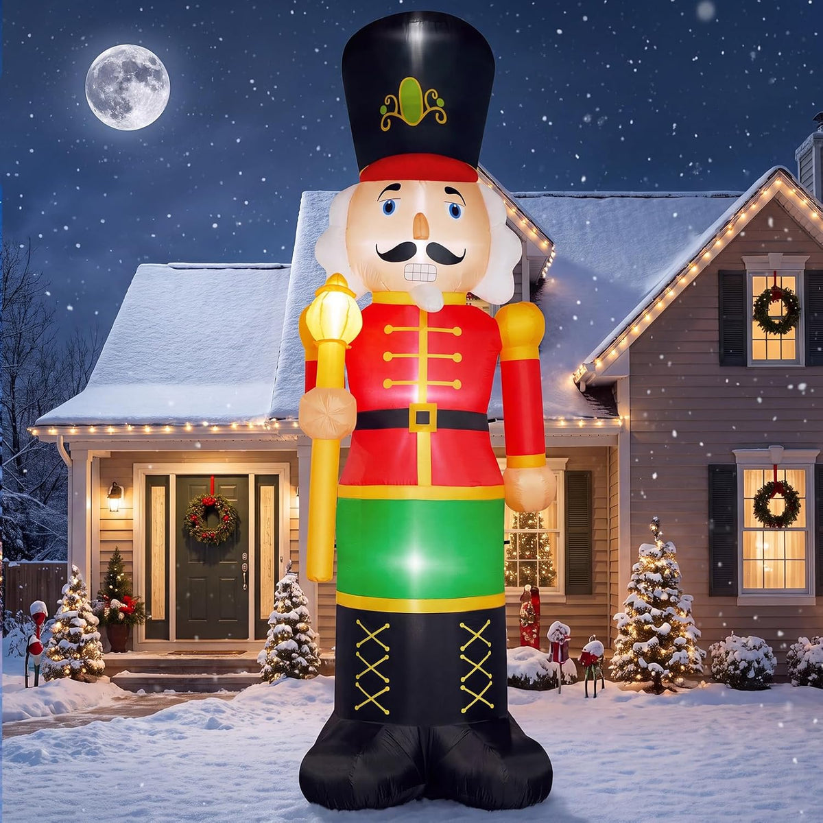 Giant nutcracker inflatable in a red coat and tall black hat in front of a snowy house at night