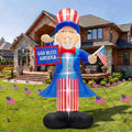 Giant Uncle Sam inflatable holding a God Bless America sign and a flag on a lawn with small flags