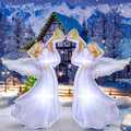 Two white angel inflatables with gold trumpets facing each other in a snowy yard