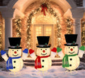 Three lighted pop-up snowmen in top hats with colored scarves in front of a decorated doorway