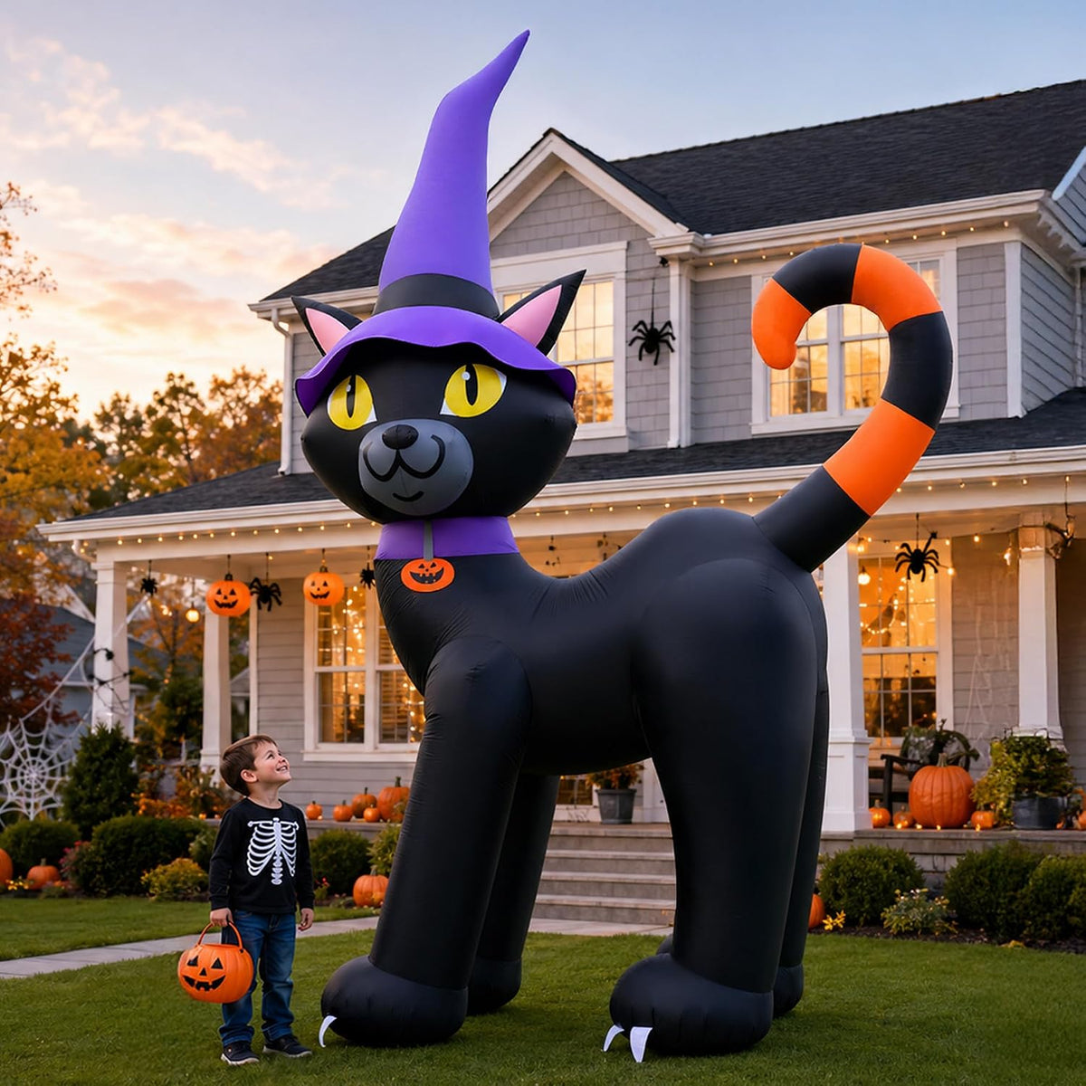 Giant black cat inflatable in a purple witch hat with an orange tail beside a child in front of a house