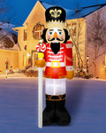 Nutcracker soldier inflatable in a red coat holding a peppermint staff in a snowy street