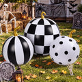 Three black and white patterned pumpkin inflatables with gold stems in a Halloween yard