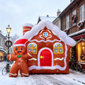 Giant gingerbread house inflatable with a red door and a waving gingerbread man on a snowy street